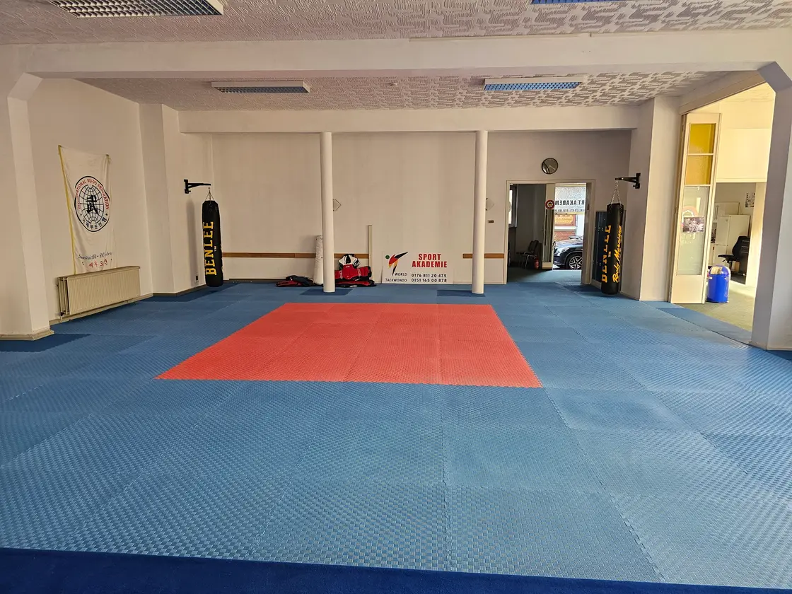 Mattenfläche der Sport Akademie mit Boxsäcken und Vereinsschild